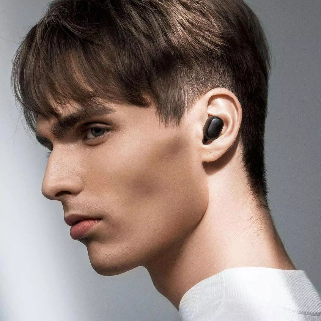 Man wearing a black wireless earbud with a neutral background