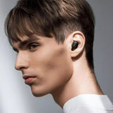 Man wearing a black wireless earbud with a neutral background