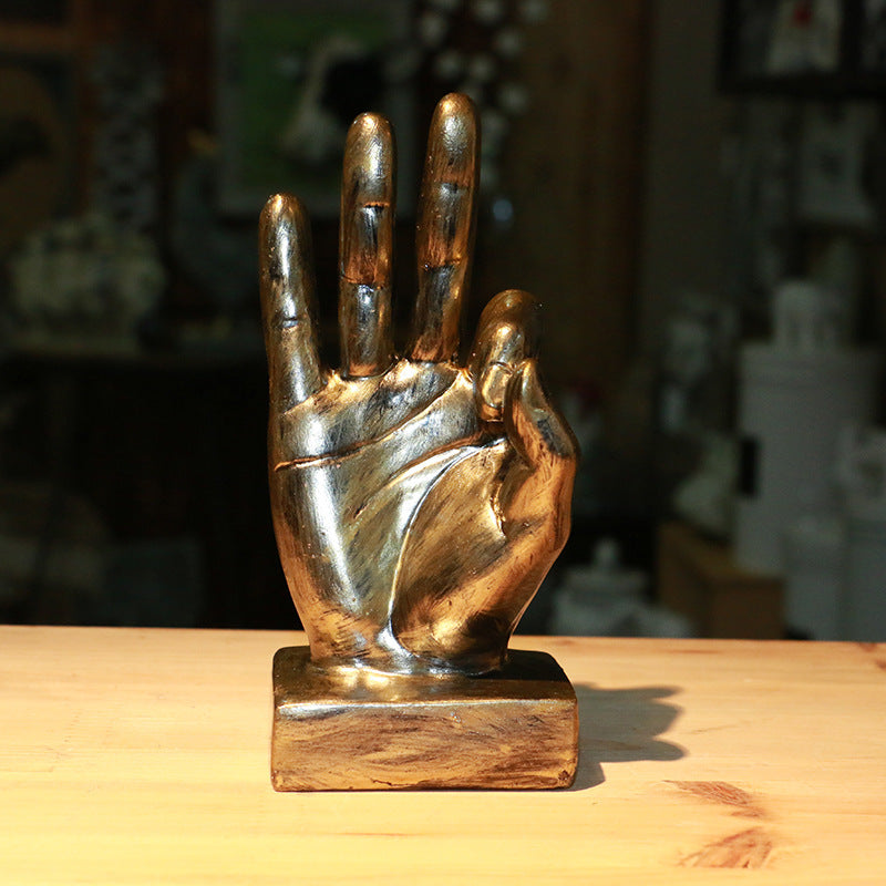 Bronze hand sculpture on a wooden base with a blurred background