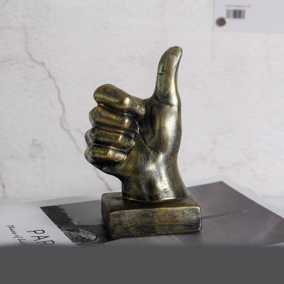 Bronze hand sculpture giving a thumbs-up on a marble surface