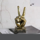 Bronze hand sculpture making a peace sign on a marble surface
