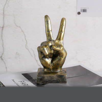 Bronze hand sculpture making a peace sign on a marble surface