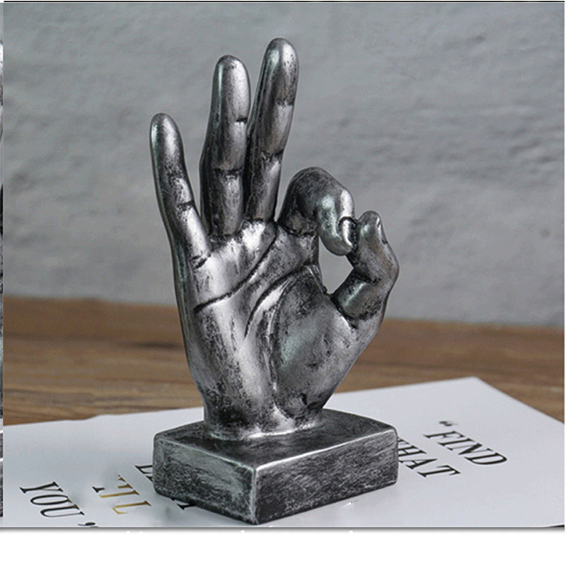 Metallic hand sculpture on a wooden surface with a blurred background