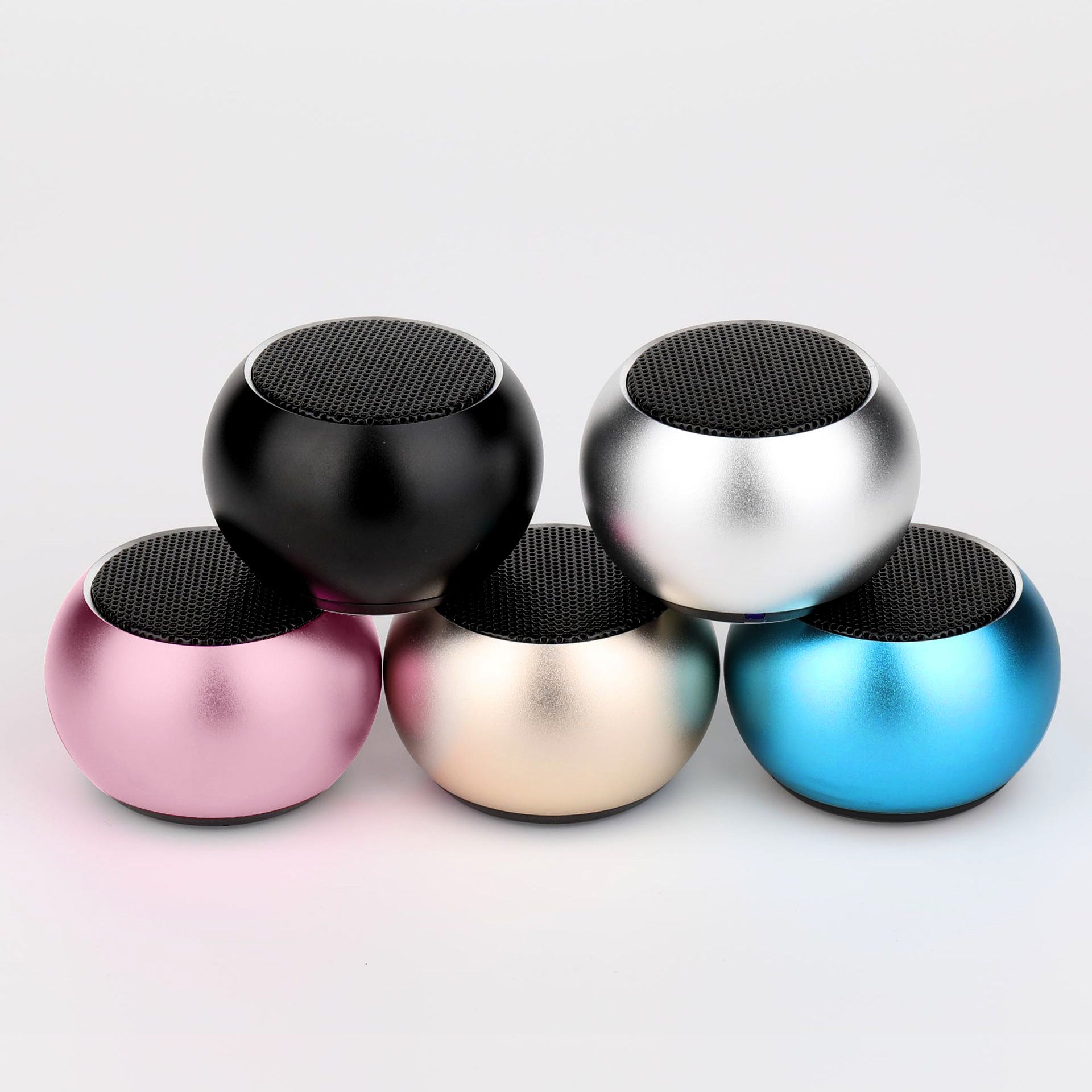 Five colorful mini speakers stacked on a light gray background