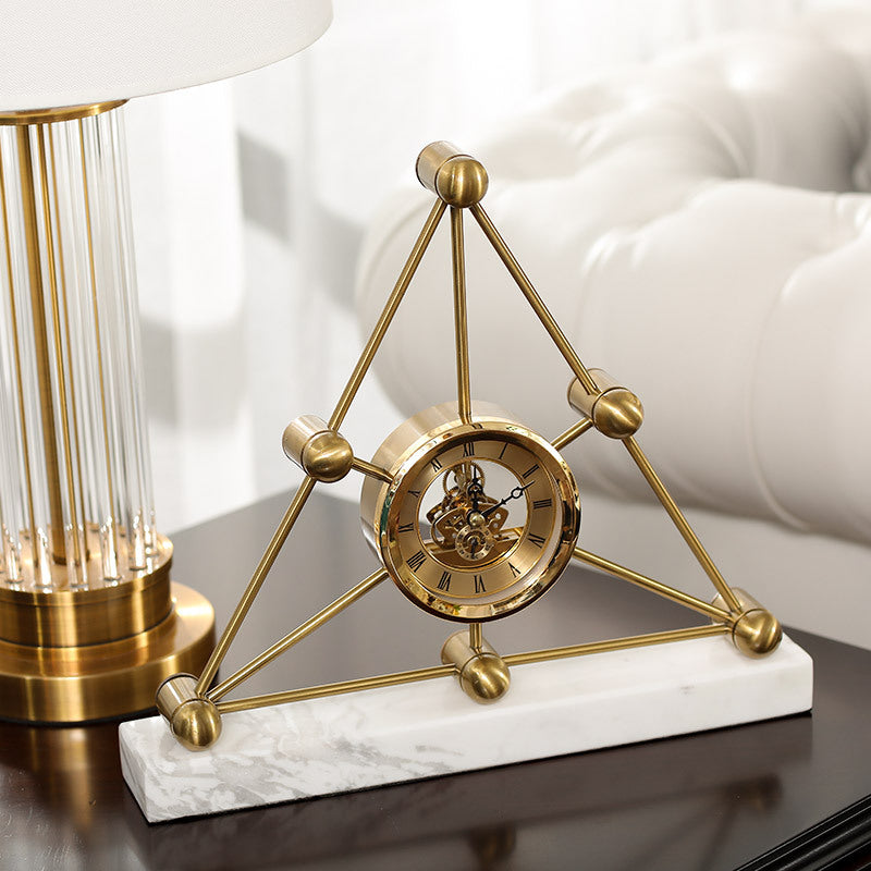 Decorative gold clock on a marble base with a lamp in the background