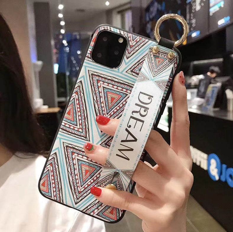 Phone case with geometric pattern and 'DREAM' strap held by a person indoors.