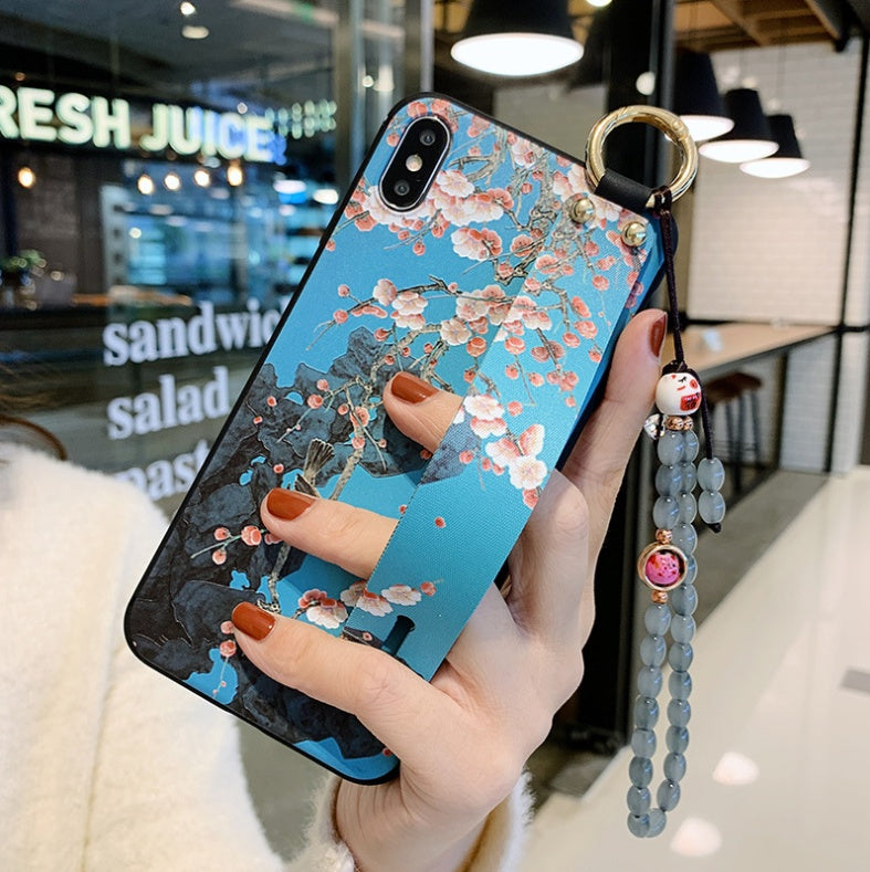 Phone case with floral design held by a hand in an indoor setting