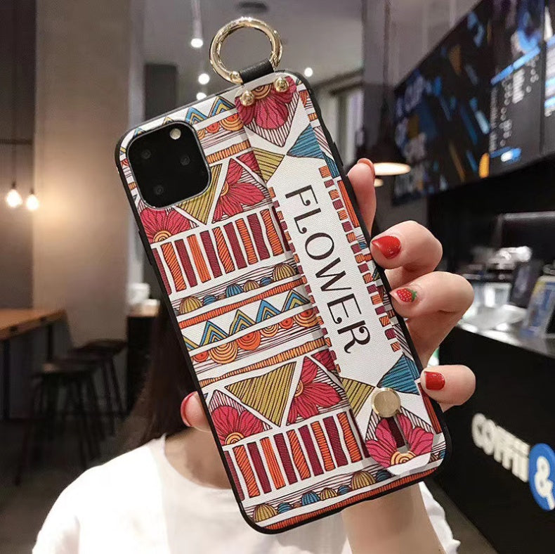 Colorful phone case with geometric patterns held by a person in a coffee shop.
