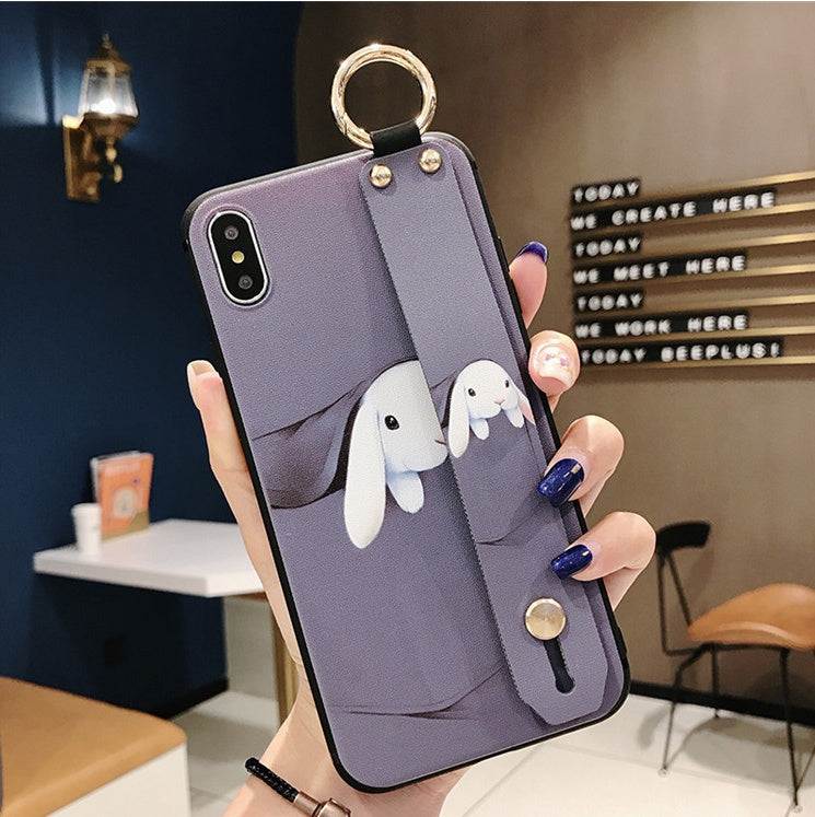 Phone case with rabbit design held by a hand in an indoor setting