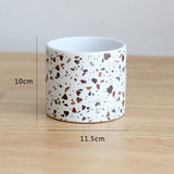 Cylindrical container with terrazzo pattern on a wooden surface, showing measurements.