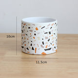 Ceramic pot with terrazzo pattern on a wooden surface, showing measurements.