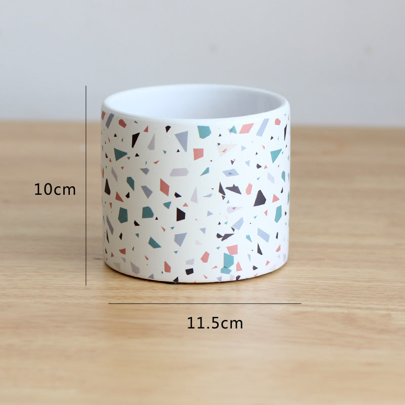 Cylindrical container with geometric pattern on a wooden surface, showing measurements.
