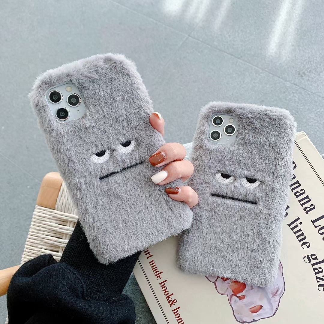 Two gray fluffy phone cases with face designs held by a person against a light gray background.