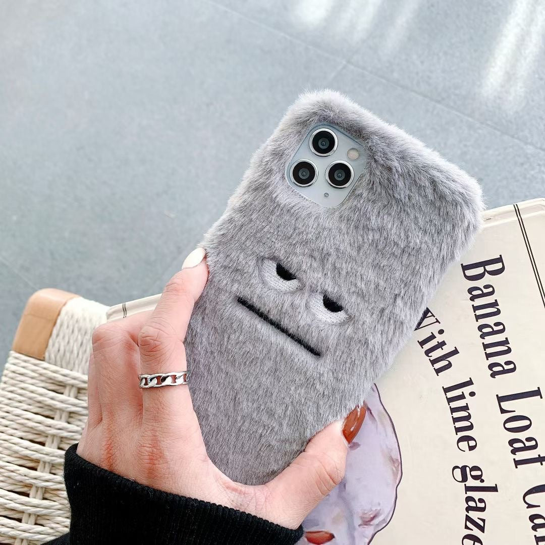 Gray fluffy phone case held by a hand on a newspaper background