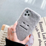 Gray fluffy phone case held by a hand on a newspaper background