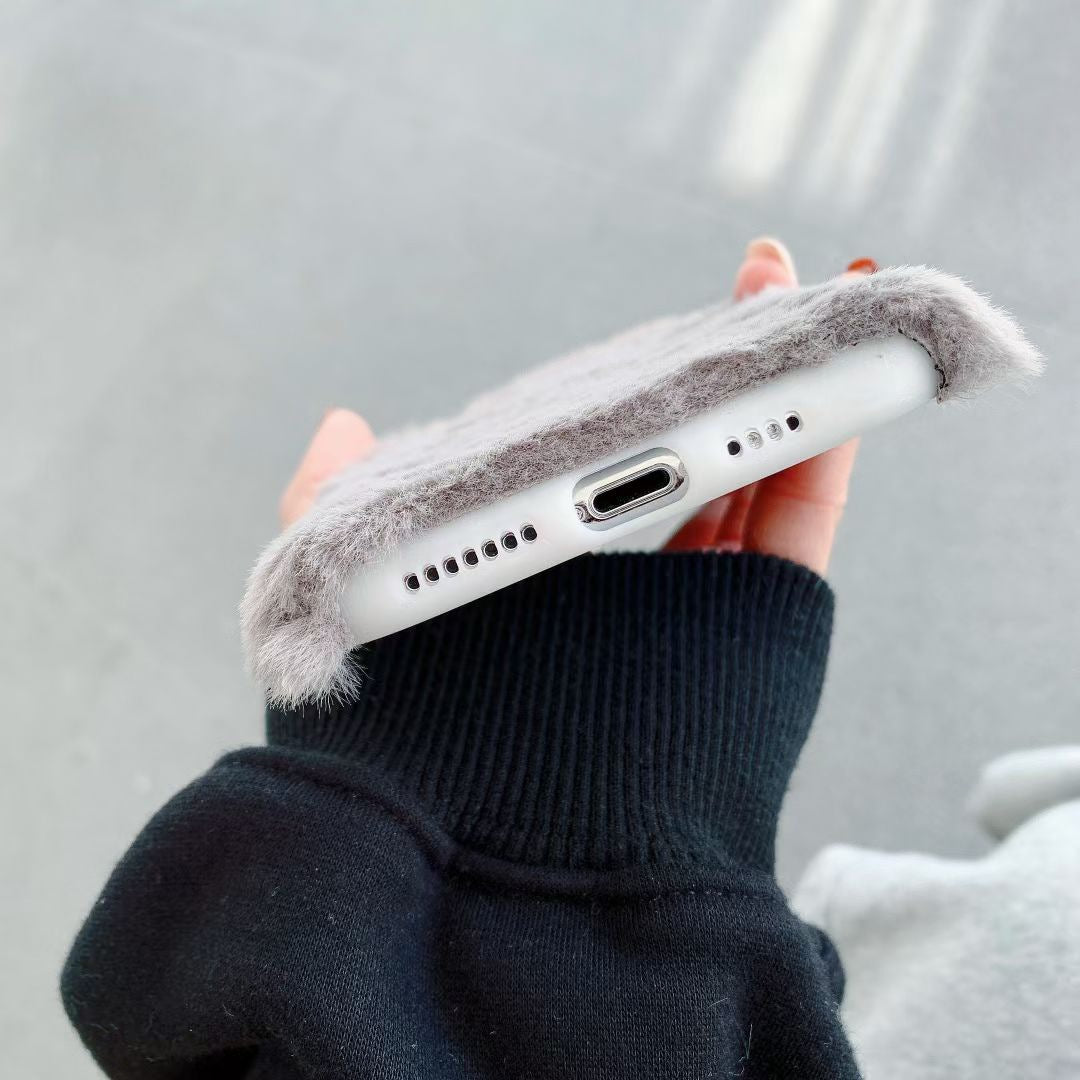 Person holding a phone with a fluffy case against a neutral background