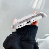 Person holding a phone with a fluffy case against a neutral background