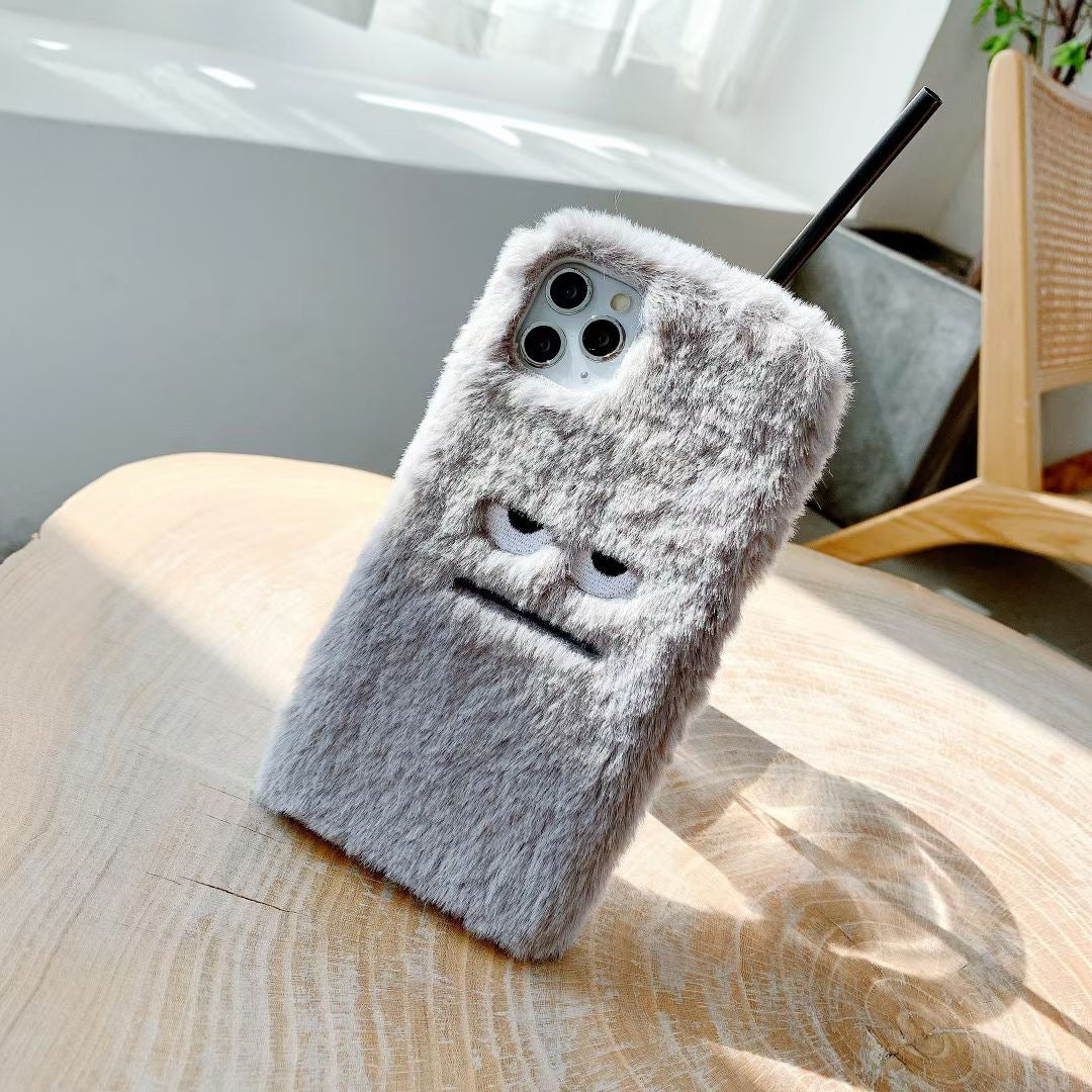 Fluffy phone case with a face design on a wooden surface