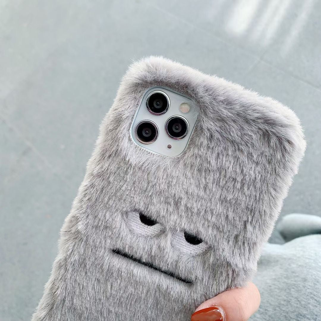 Gray fluffy phone case with a cute design held by a hand against a light gray background