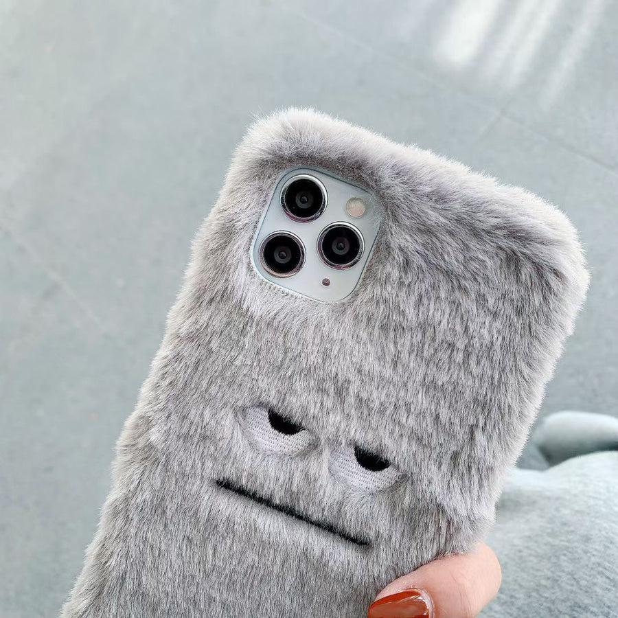 Gray fluffy phone case with a cute design held by a hand against a light gray background