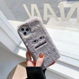 Gray textured phone case with cartoon face held by a hand against a blurred background
