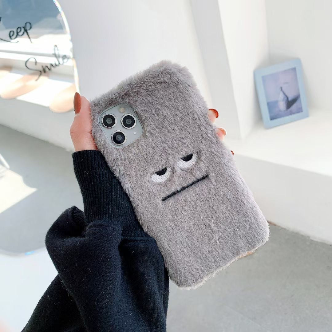 Person holding a phone with a fluffy gray case featuring a face design.