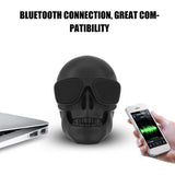 Skull-shaped Bluetooth speaker with smartphone and laptop on a white background