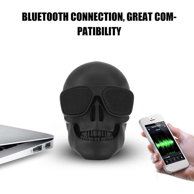Skull-shaped Bluetooth speaker with smartphone and laptop on a white background