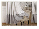 Gray and white curtain draped over a chair in a room with a patterned wall.