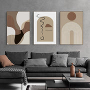 Abstract art prints on a gray wall above a gray sofa with decorative pillows.