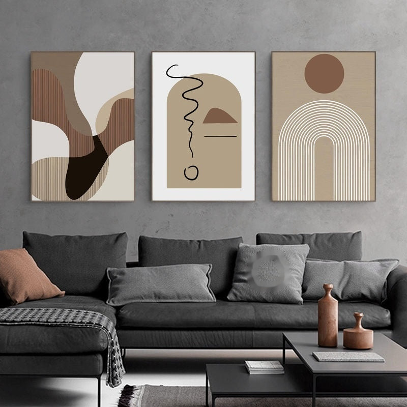 Abstract art prints on a gray wall above a gray sofa with decorative pillows.
