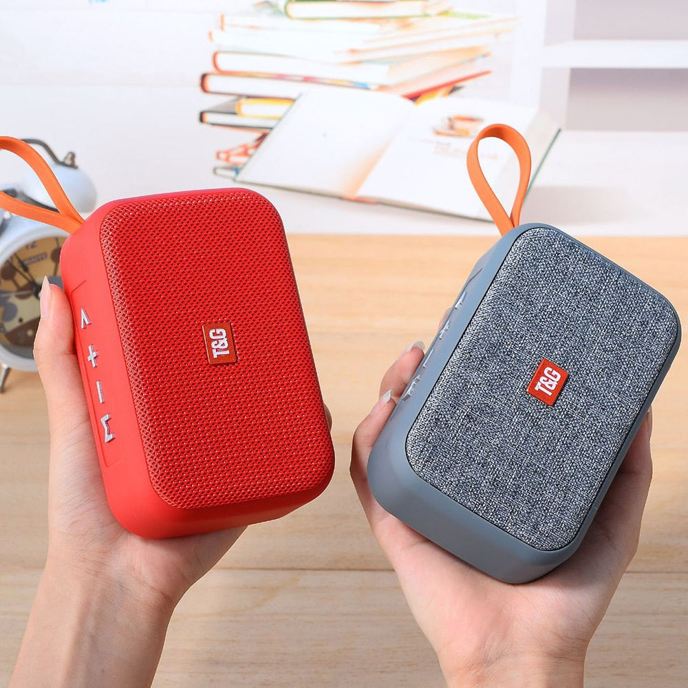 Two portable speakers, one red and one gray, held in hands with a blurred background.