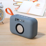 Gray portable speaker on a wooden surface with a blurred background