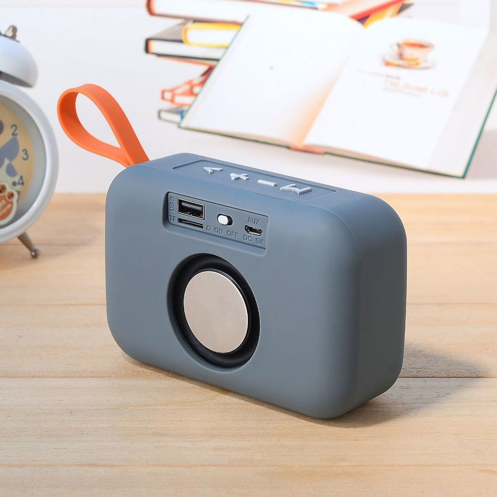 Gray portable speaker on a wooden surface with a blurred background
