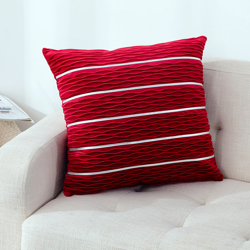 Red textured pillow on a beige sofa with a white background