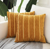 Two mustard yellow textured pillows on a white sofa with plants in the background.