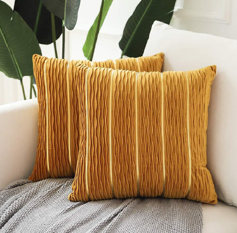 Two mustard yellow textured pillows on a white sofa with plants in the background.