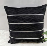 Black textured pillow with white stripes on a light background