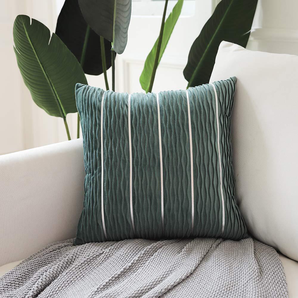 Green striped pillow on a white couch with plants in the background