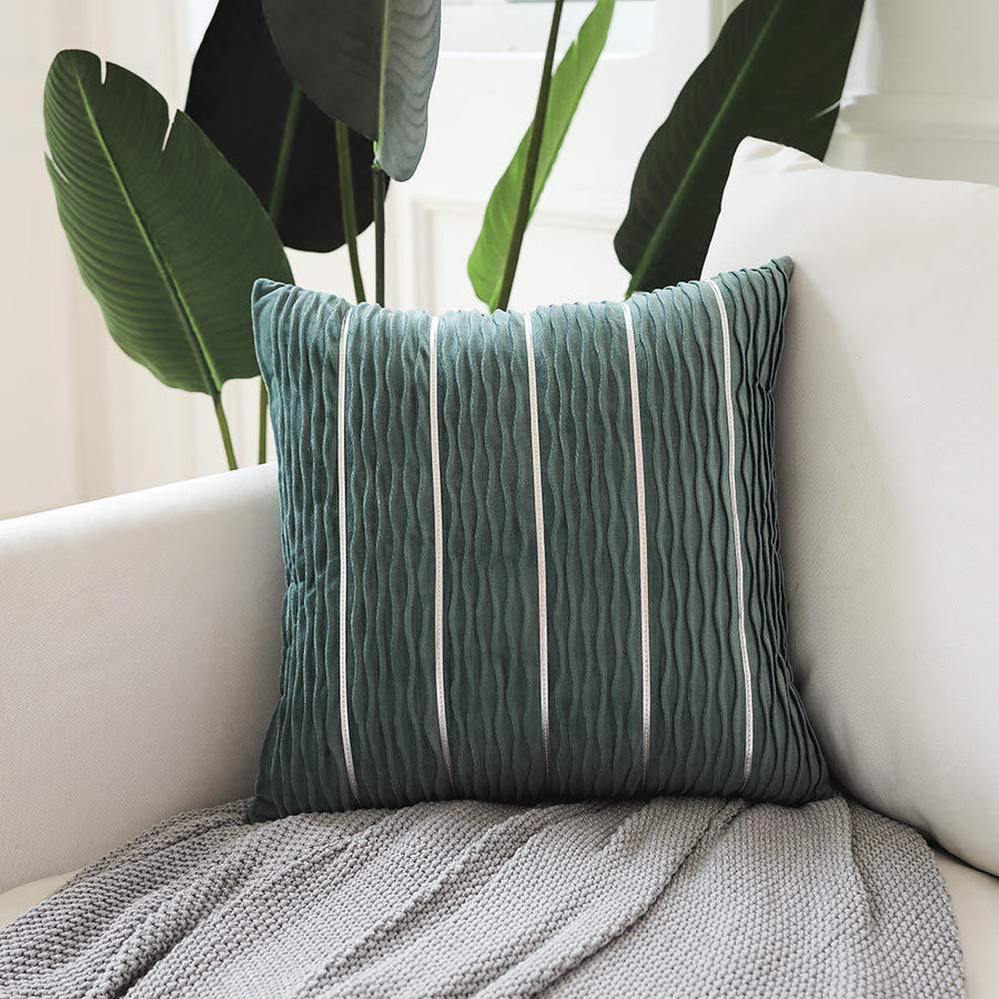 Green striped pillow on a white couch with plants in the background