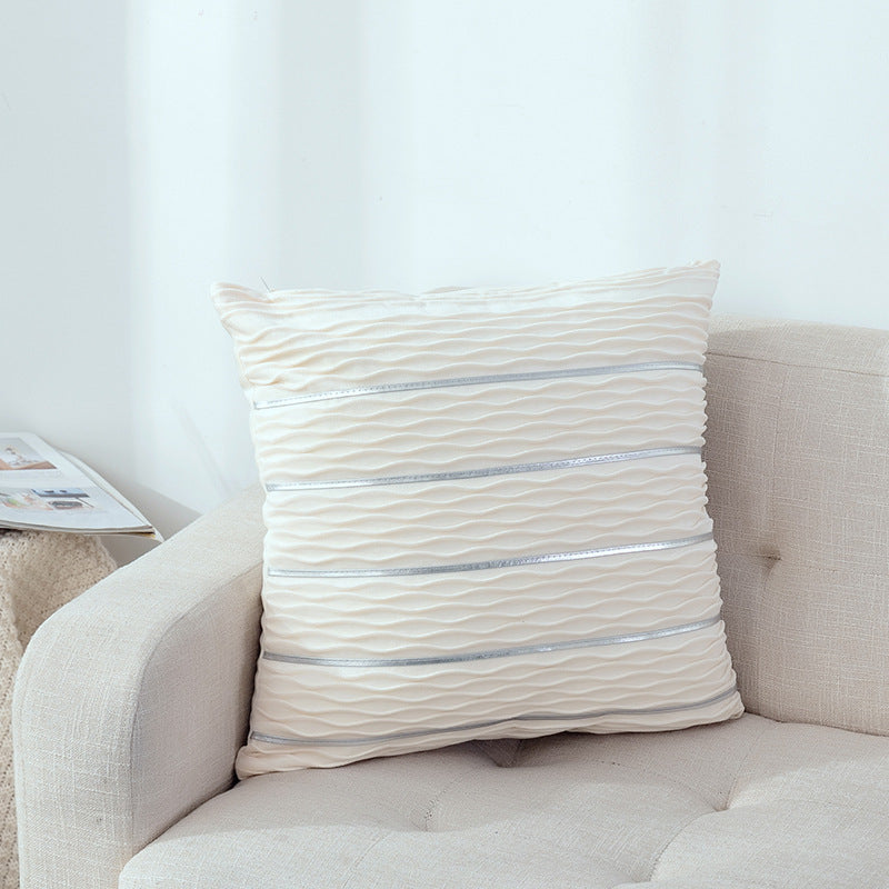 Beige pillow with horizontal stripes on a beige sofa against a white wall.