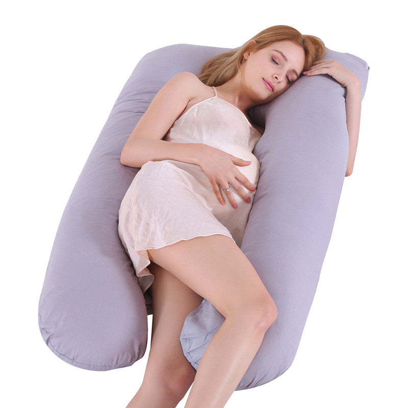 Woman lying on a large U-shaped pillow against a white background
