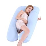 Woman lying on a large U-shaped blue pillow against a white background