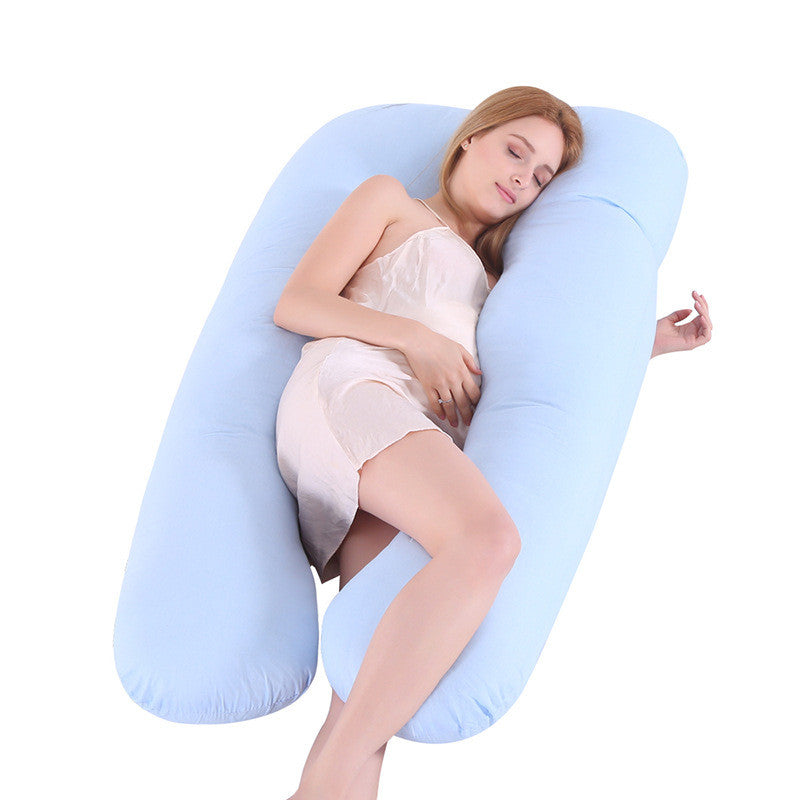 Woman lying on a large U-shaped blue pillow against a white background