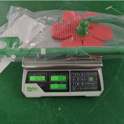 Green broom with red bristle head on a digital scale against a green background