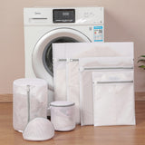 Set of laundry bags in front of a washing machine on a wooden floor.