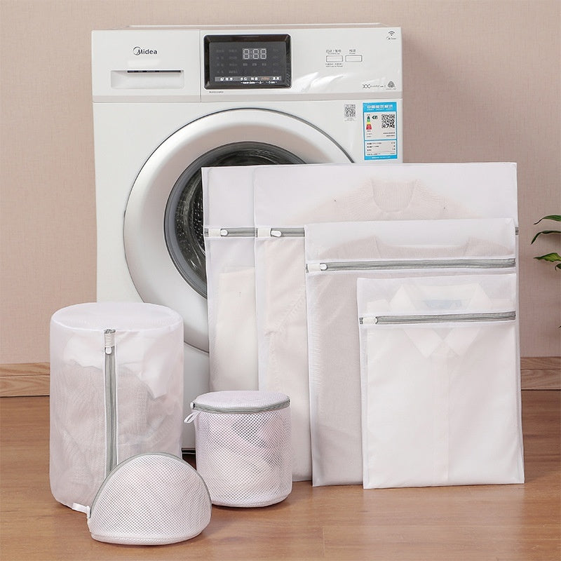 Set of laundry bags in front of a washing machine on a wooden floor.