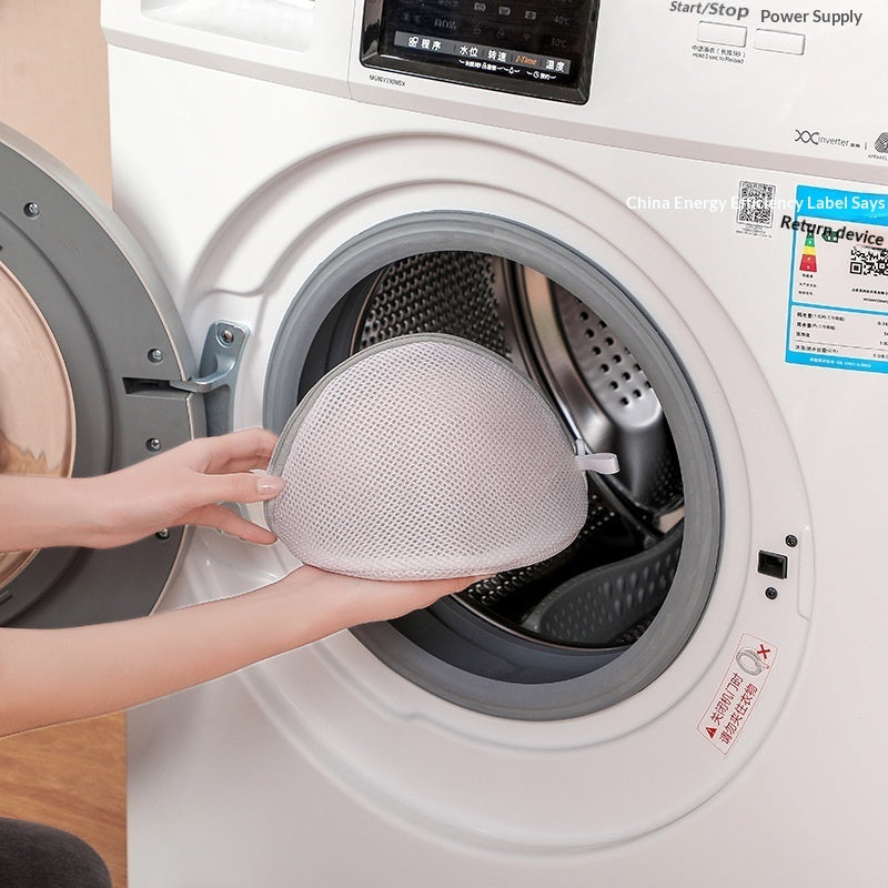 Person holding a bra mesh in front of an open washing machine.