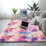 Colorful rug in a living room with a laptop, plant, and coffee cup.