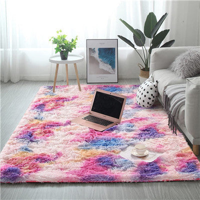 Colorful rug in a living room with a laptop, plant, and coffee cup.